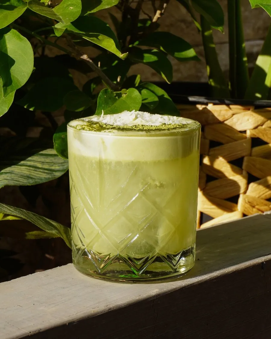 Matcha latte de Sabina en vaso de vidrio, entre plantas